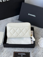 White quilted small bag with gold zip and attached wrist strap loop