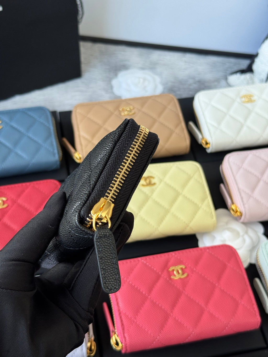 Small quilted zip wallet in black leather with gold zipper and zipper pull detail.
