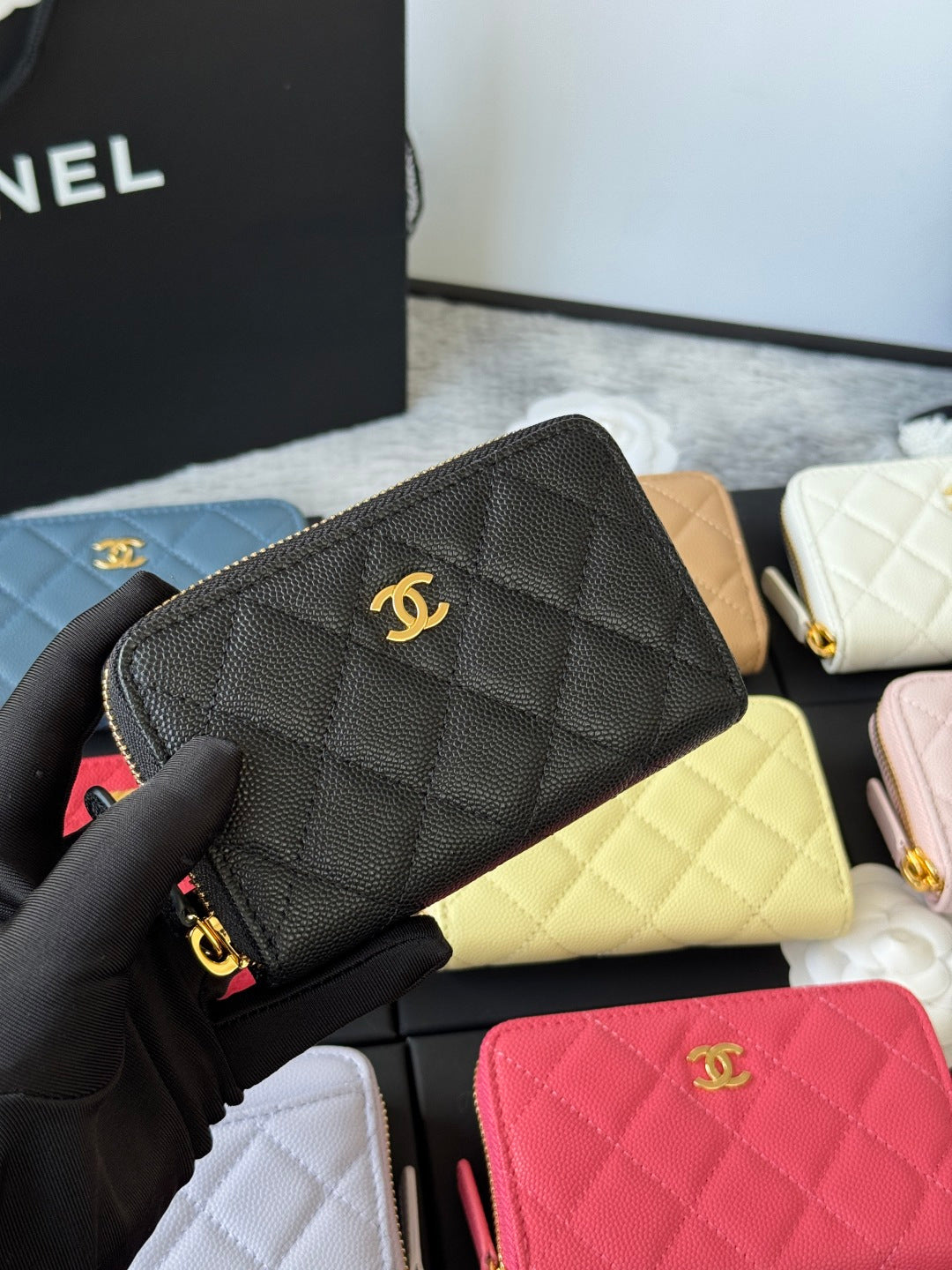 Small quilted zip wallet in dark gray/black leather with gold CC logo and zipper.