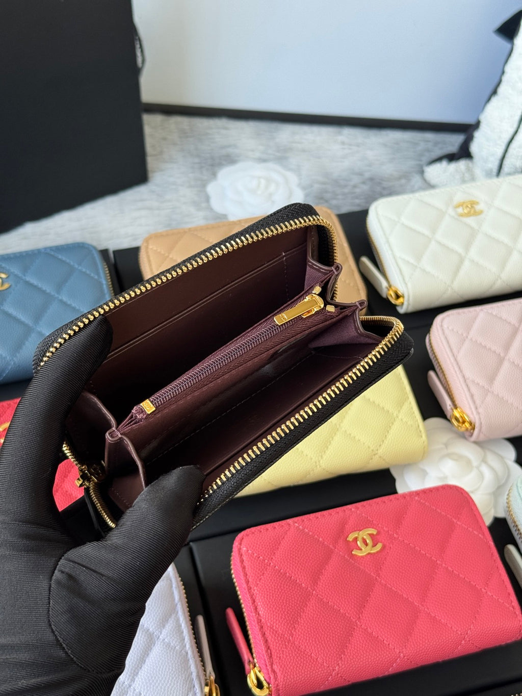 Small quilted zip wallet opened to show dark interior lining and dual zipper compartments.