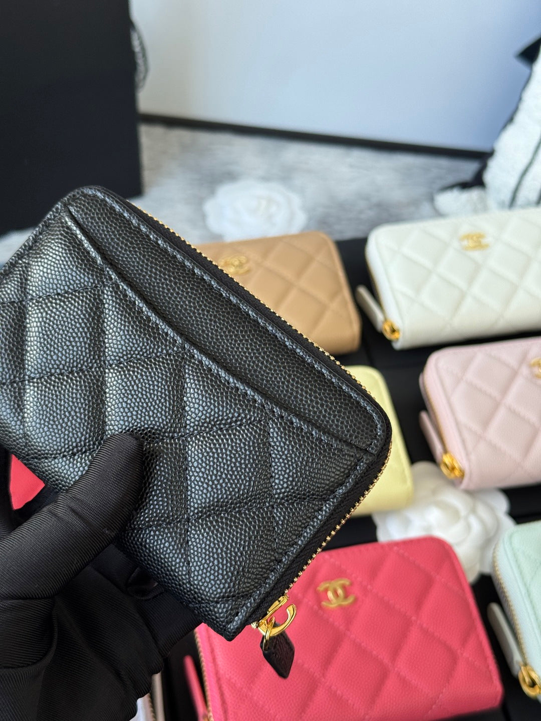 Small quilted zip wallet in textured black leather with gold zipper and side profile.
