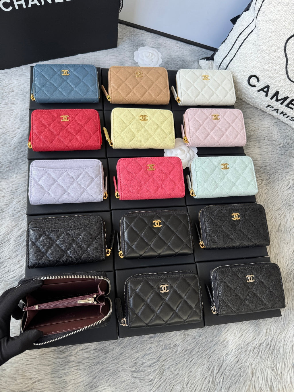 Assorted small quilted zip wallets in multiple colors, arranged in rows with gold logos.