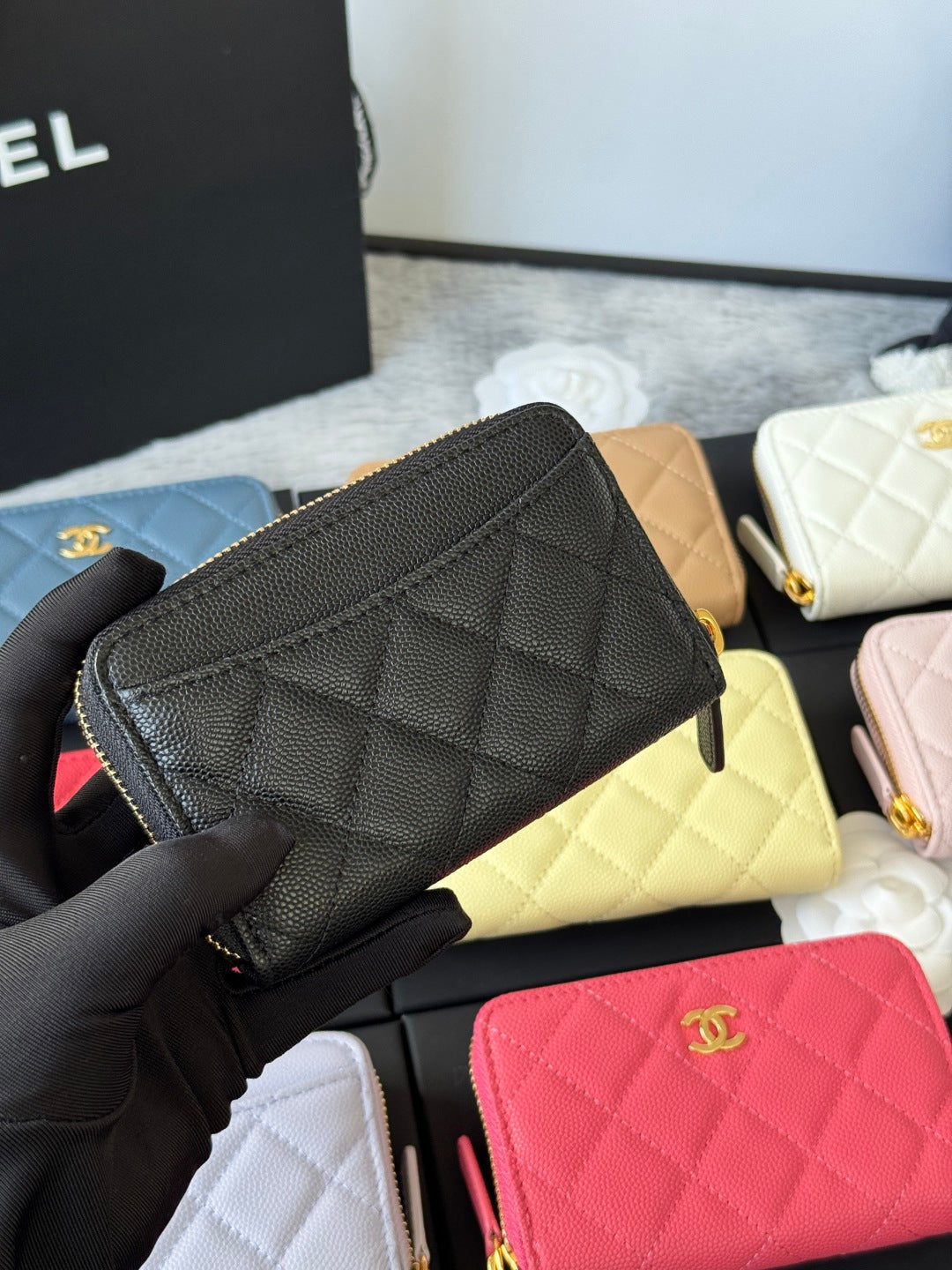 Small quilted zip wallet in textured black leather with gold zipper pull and CC logo.