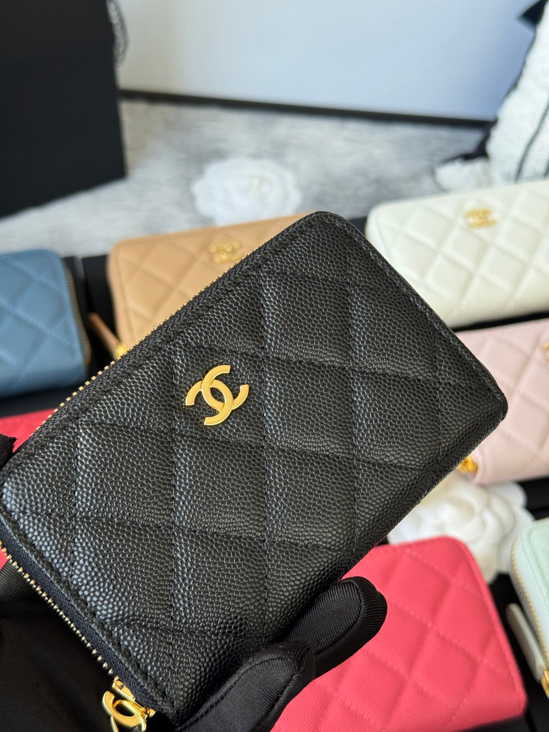 Small quilted zip wallet in textured black leather with centered gold CC logo front.