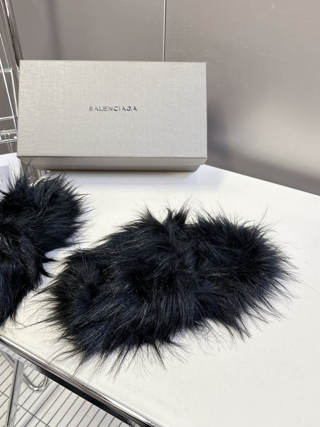 Pair of black fuzzy slide sandals with wide strap and visible Balenciaga branding