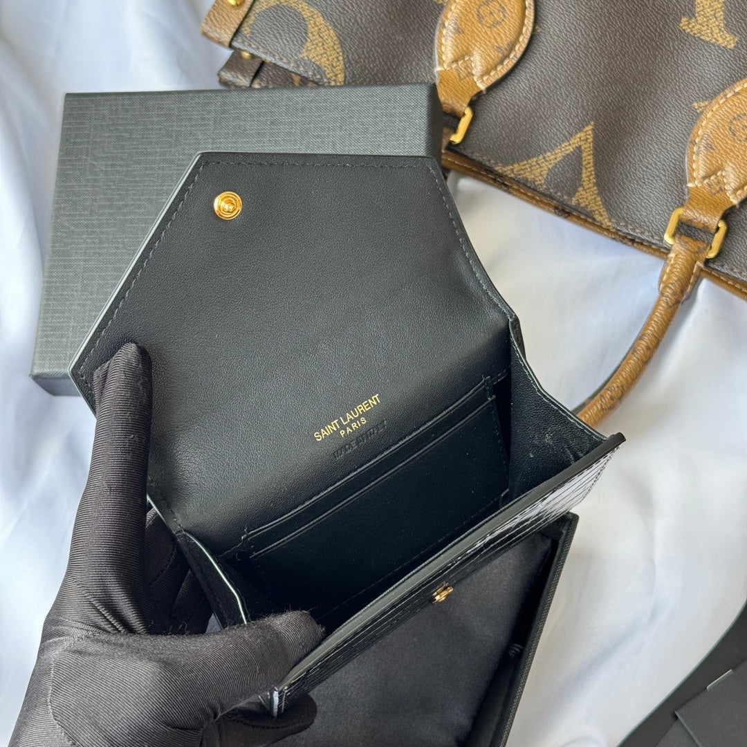 Small bag front view with black leather finish, gold snap button and SAINT LAURENT text