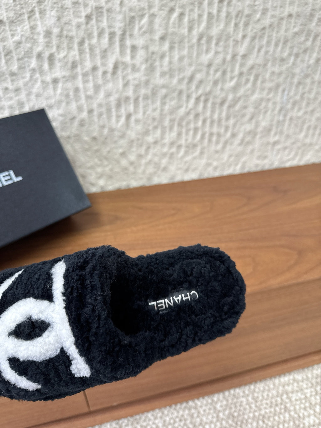 Black plush slide sandal with white logo and small side text