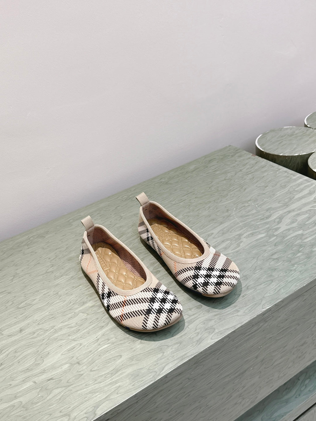 Plaid slip-on shoes on a light surface, front view of pair