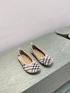 Plaid slip-on shoes on a light surface, front view of pair