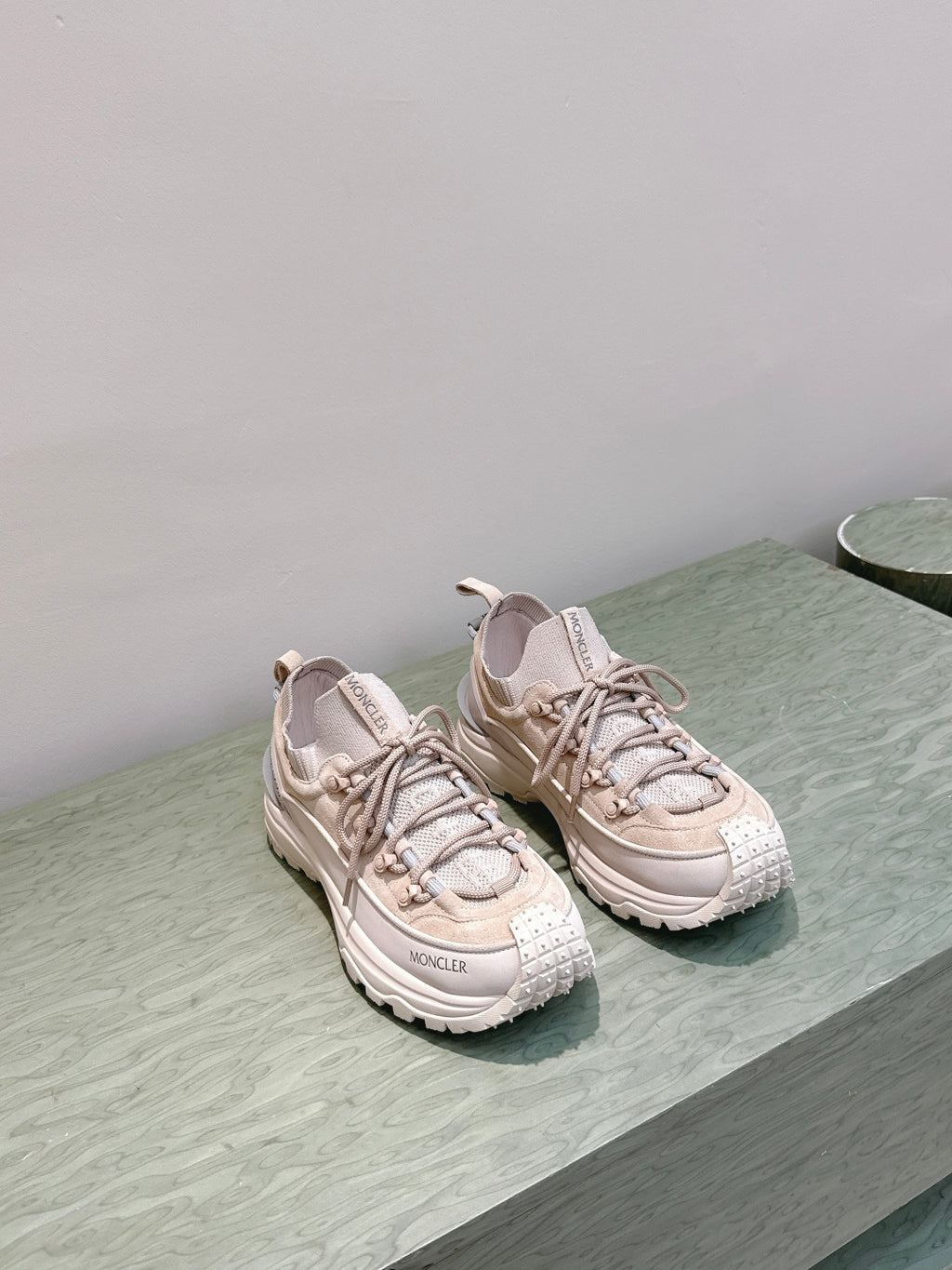 Moncler light beige sneakers with chunky soles, side-by-side on shelf