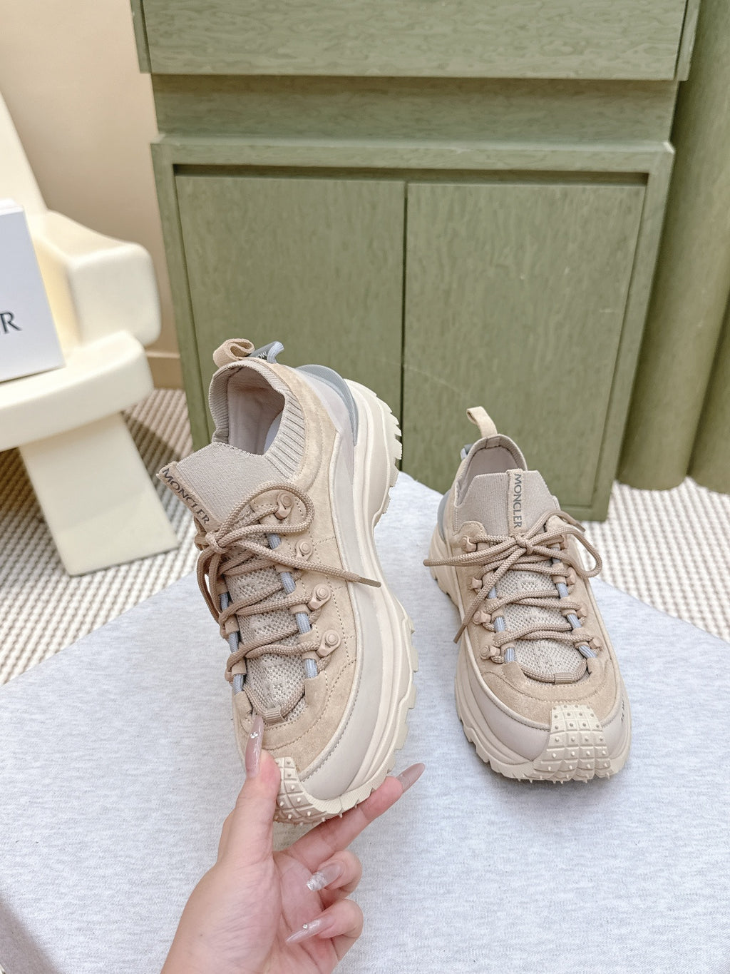 Moncler light beige sneaker held by hand, lace-up with padded collar and heel logo