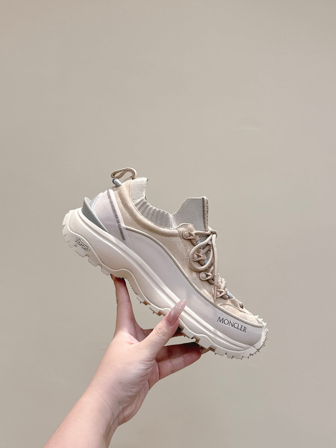 Moncler cream sneakers held in hand, lace-up runner style with chunky outsole