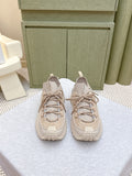 Moncler light beige sneakers with lace-up front, chunky sole, and logo tab at tongue