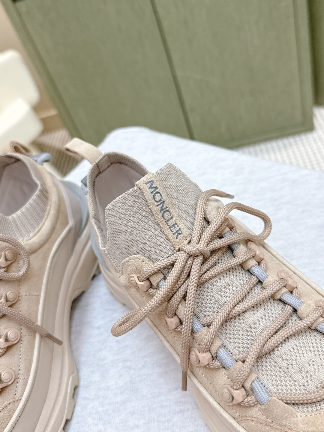 Moncler logo patch on light beige sneaker tongue, lace eyelets and textured knit upper