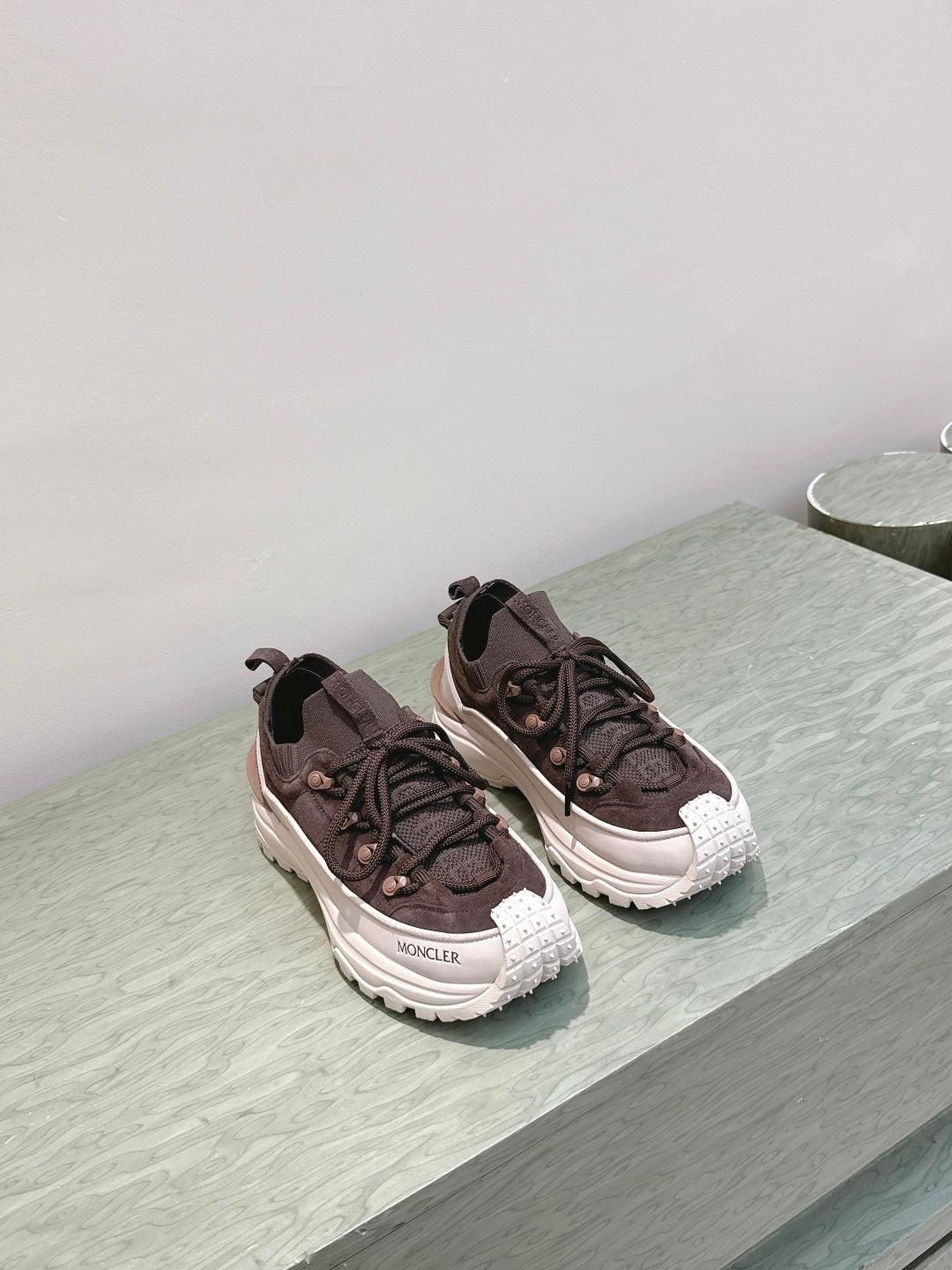 Dark brown lace-up sneakers with chunky white soles, side-by-side pair on ledge