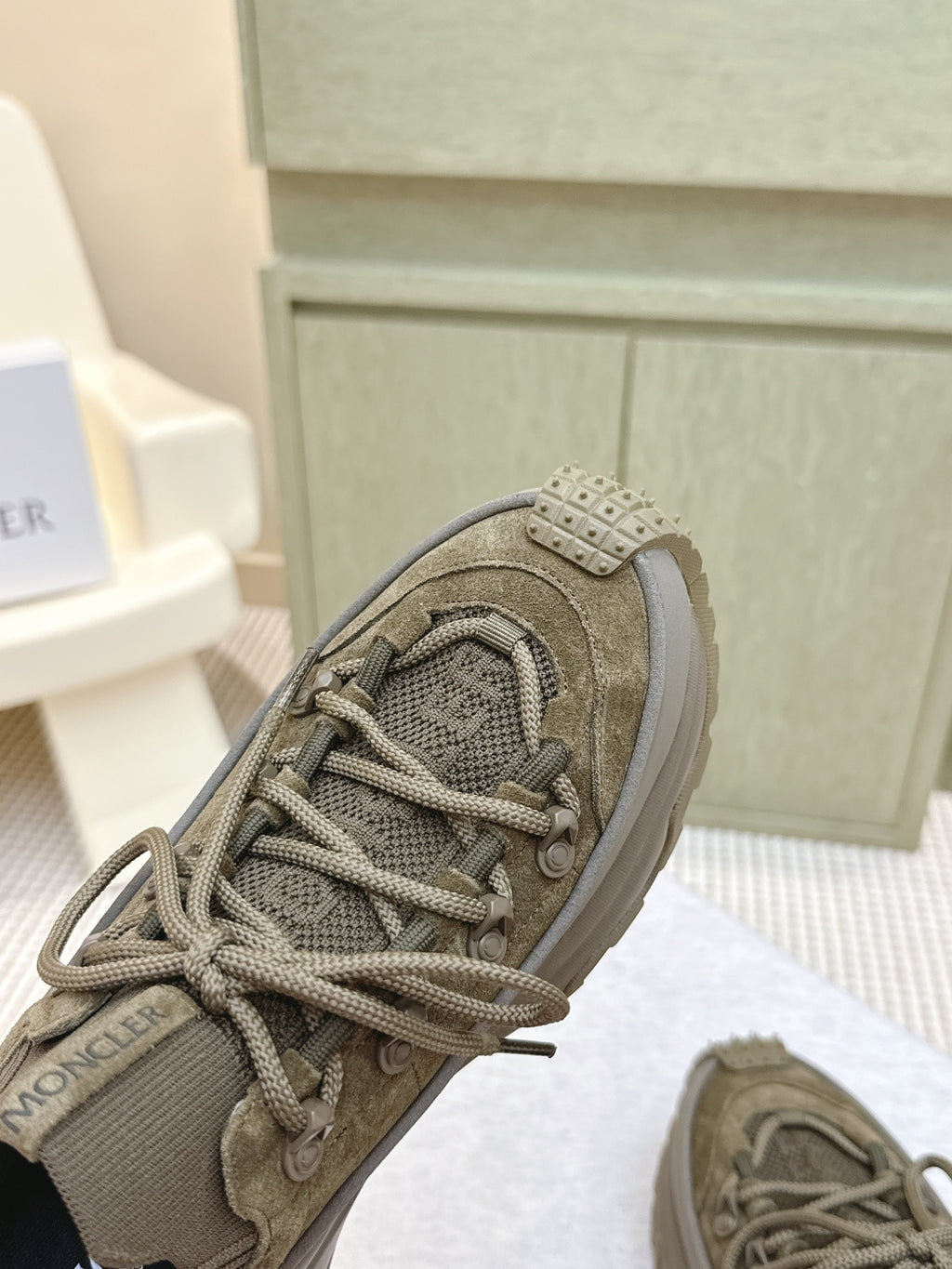 Moncler olive running sneaker close-up with lace-up and studded strap detail
