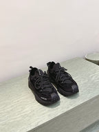 Black Moncler lace-up sneakers on light surface, side-angle view