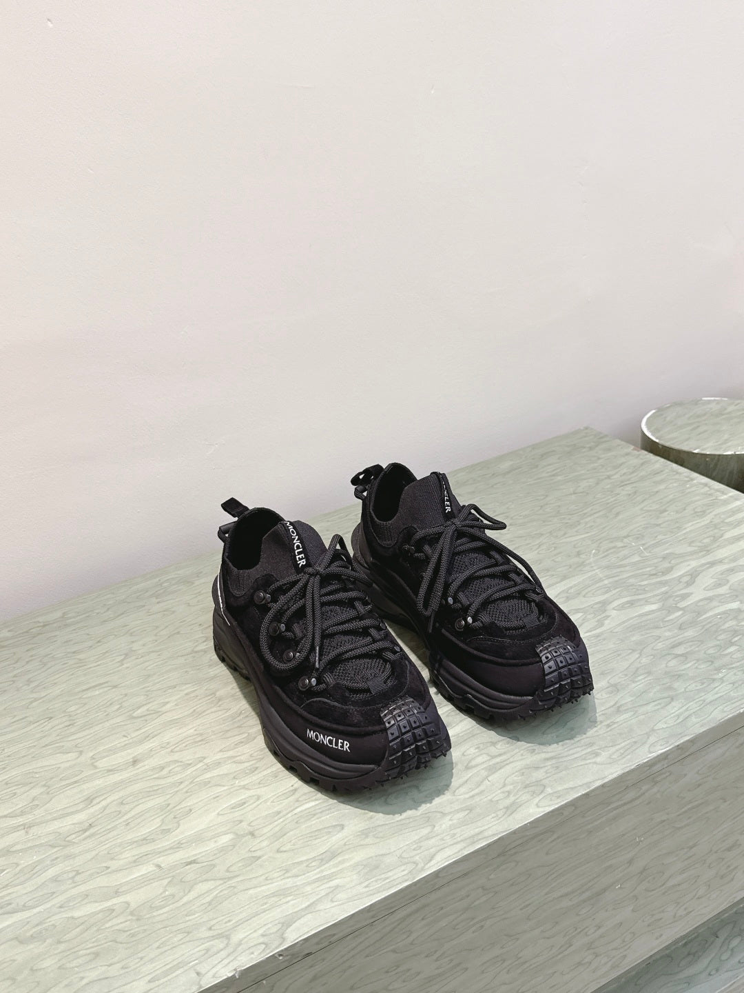 Black Moncler lace-up sneakers on light surface, side-angle view
