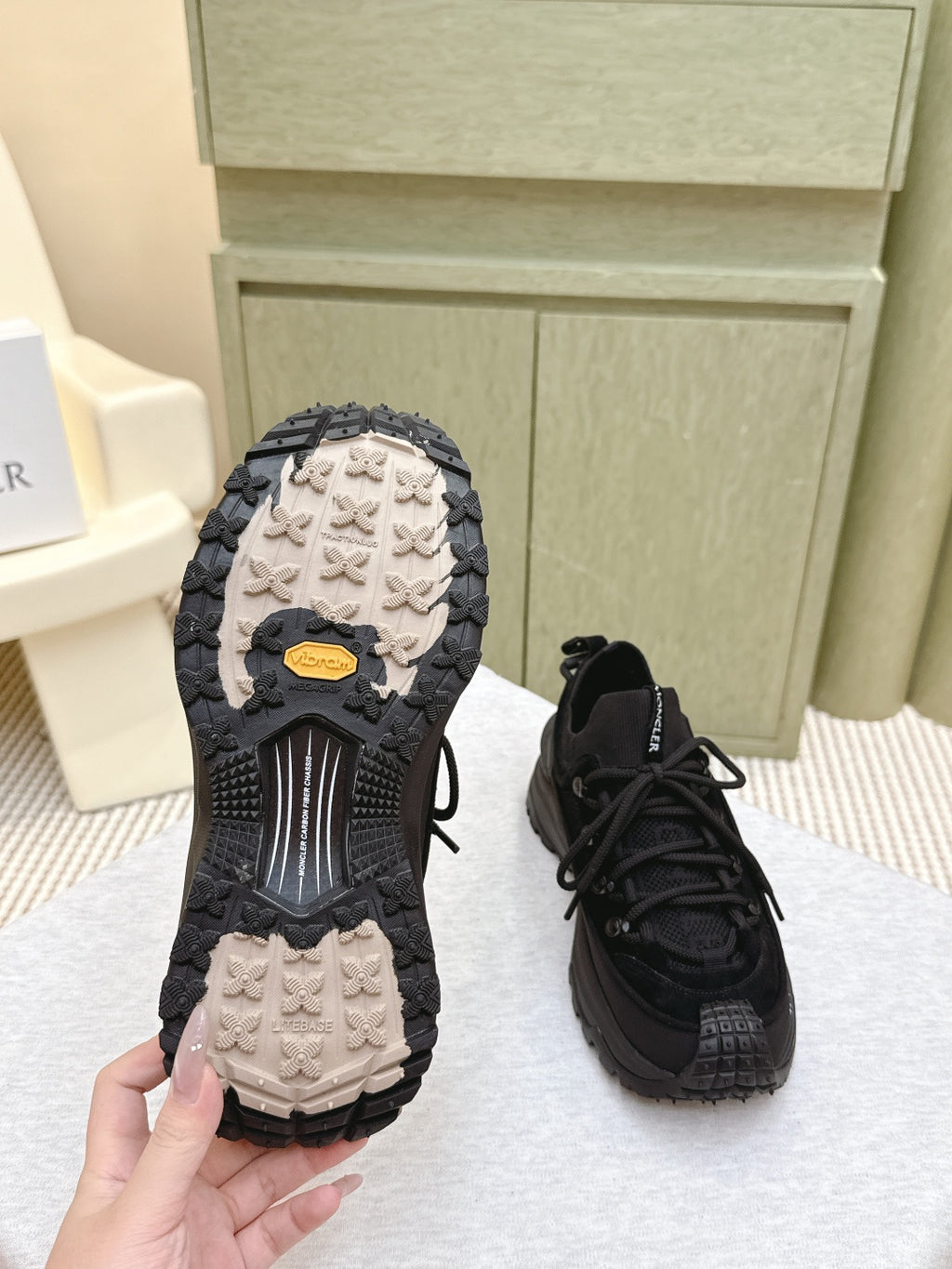 Black Moncler sneaker pair, outsoles visible with light tread pattern