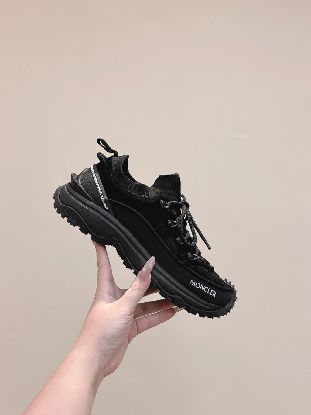 Black Moncler chunky lace-up sneaker held in hand, side profile view
