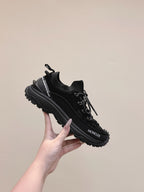 Black Moncler chunky lace-up sneaker held in hand, side profile view