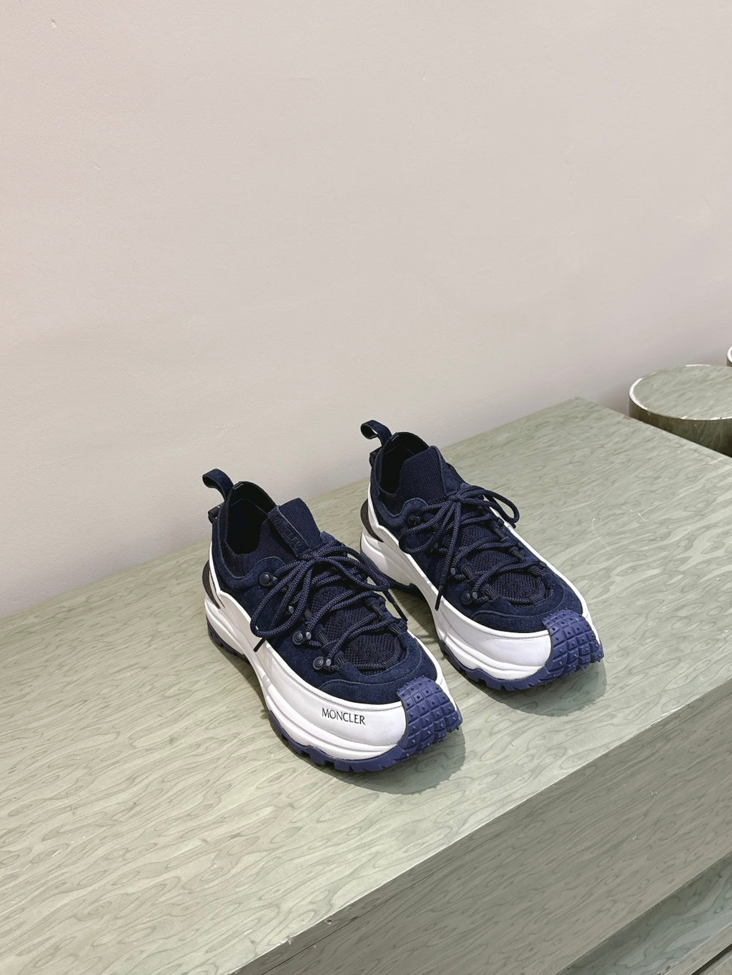 Navy sneakers on display with white midsoles and black laces, angled view