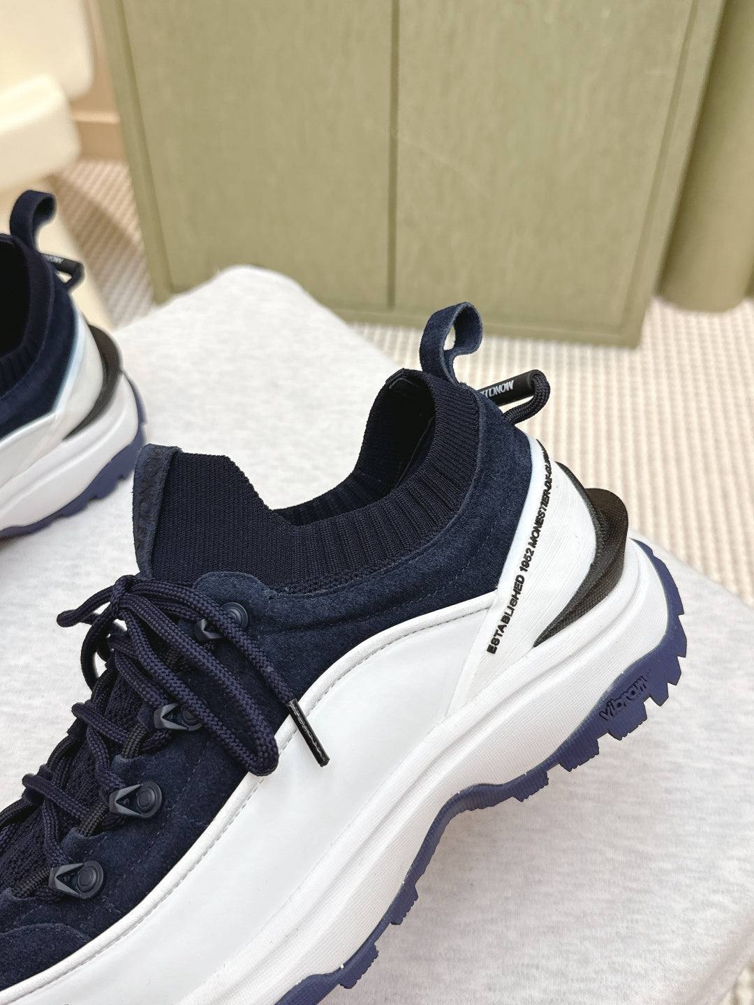 Navy sneaker with sock-style collar and white side stripe, side view