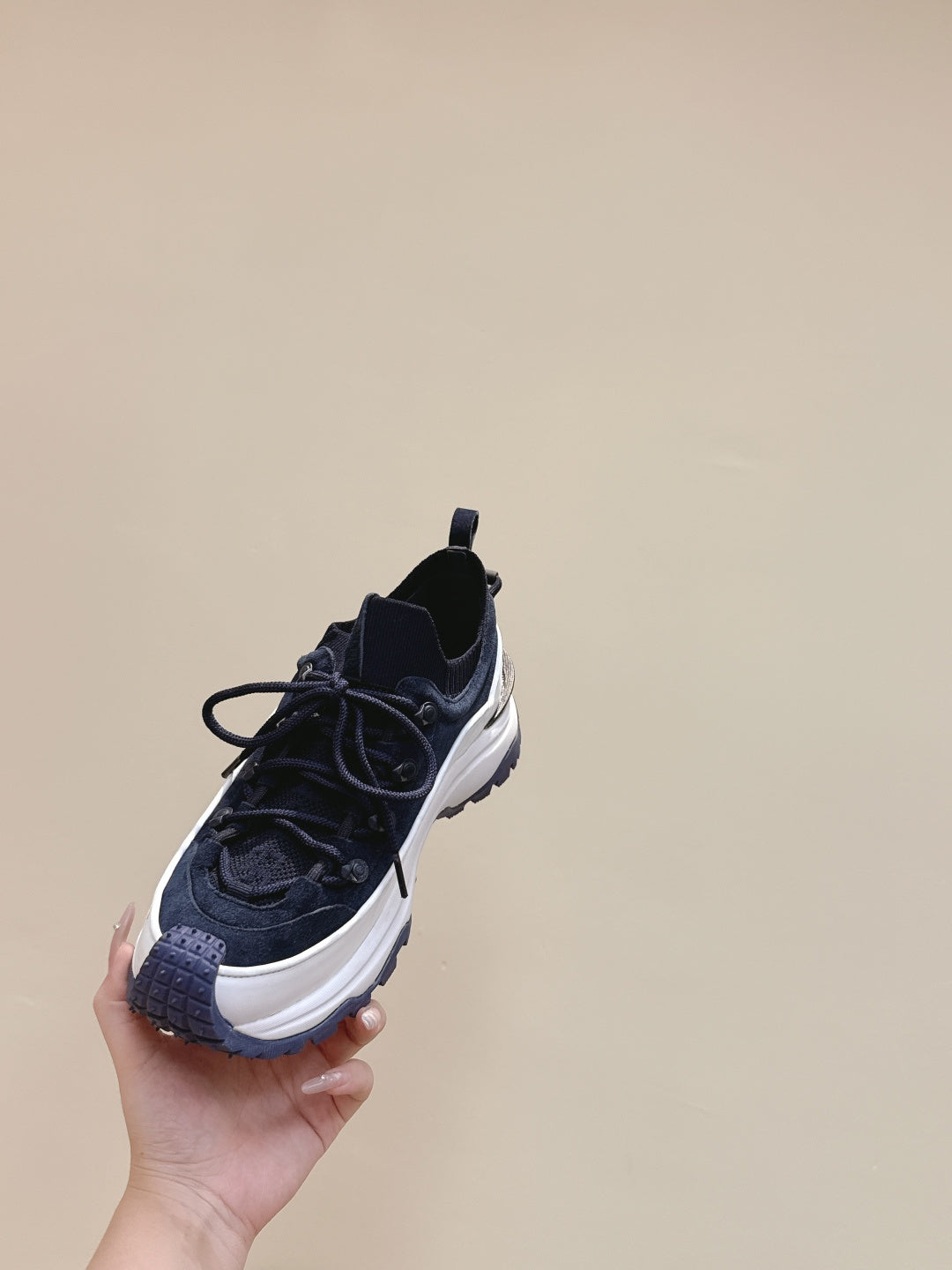 Navy sneaker with white midsole and logo detail, angled side view