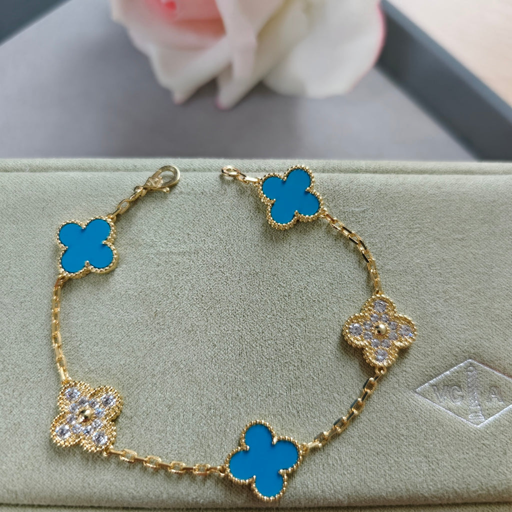 Gold bracelet with blue clover links and three sparkling flower charms, adjustable clasp