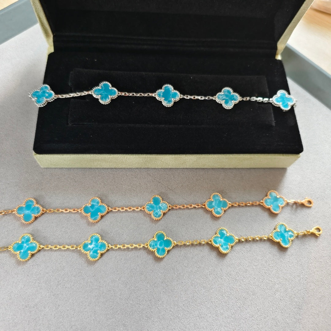 Van Cleef & Arpels clover charm bracelets on display, gold and silver tones, blue enamel