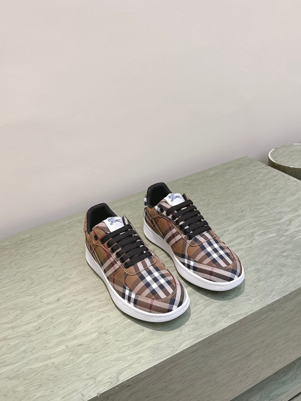 Burberry sneakers on display, brown plaid uppers with black laces and white soles