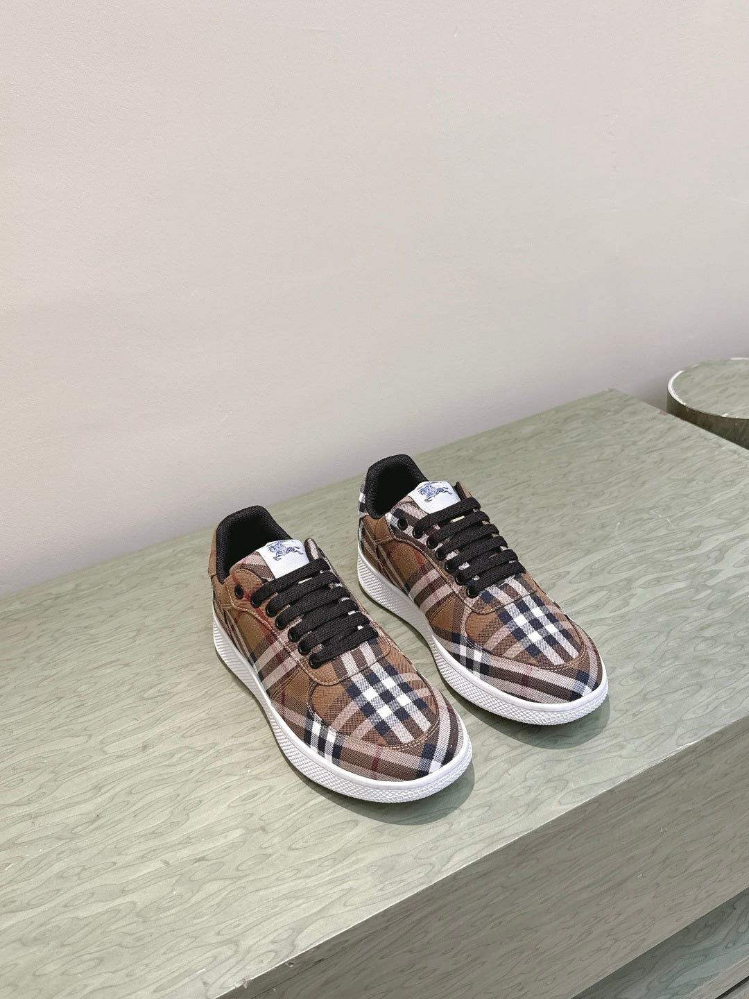 Burberry sneakers on display, brown plaid uppers with black laces and white soles