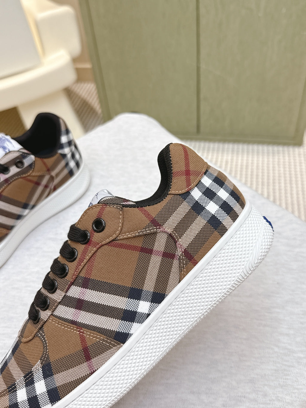 Burberry sneaker close-up, brown plaid fabric with black laces and round eyelets