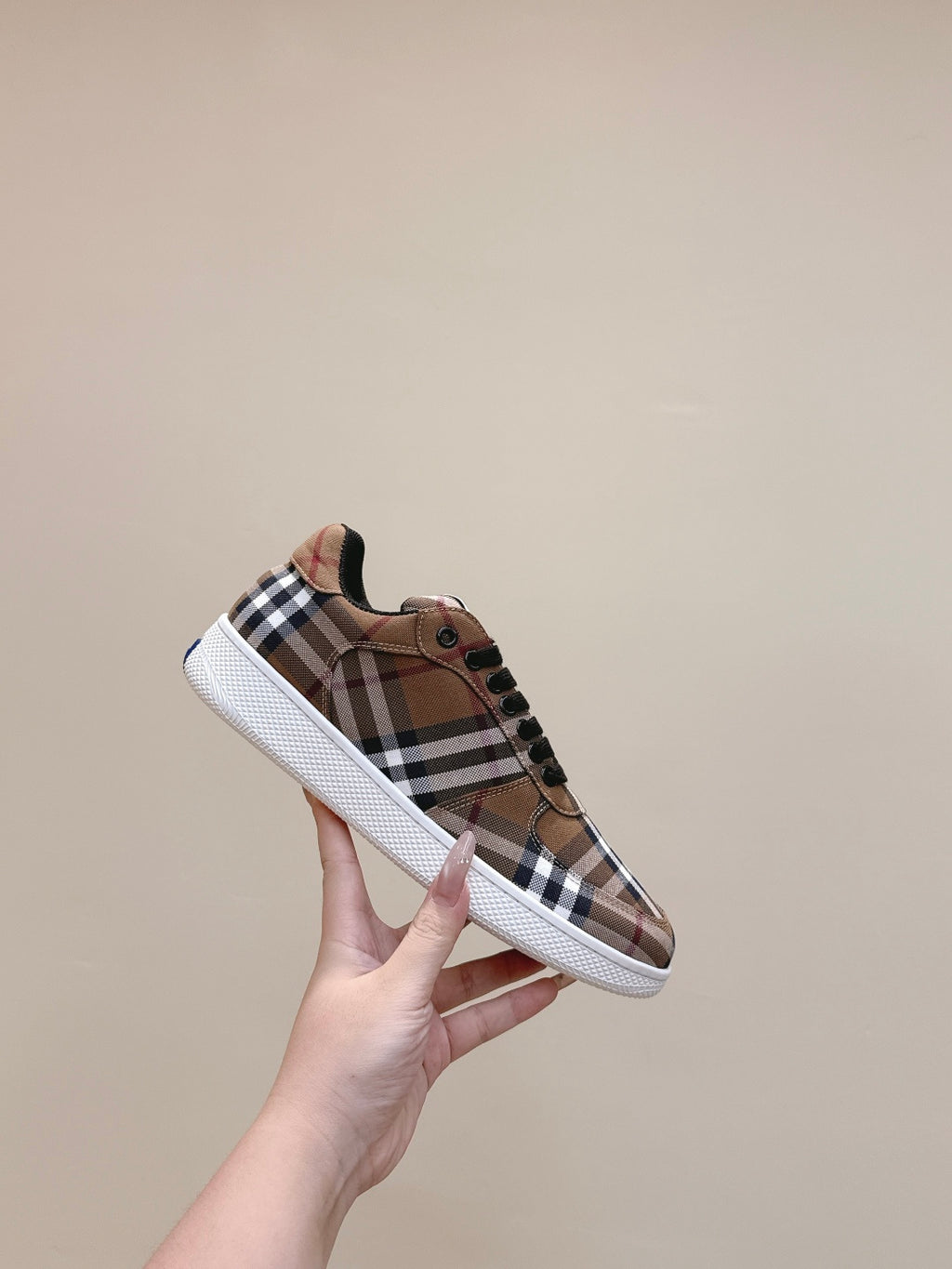 Burberry sneakers held up, brown plaid upper with black laces and white sidewall sole
