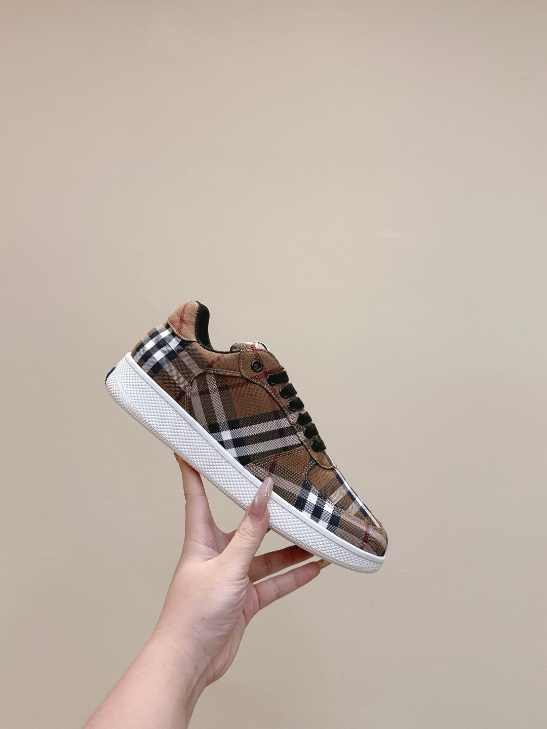 Burberry sneakers held up, brown plaid upper with black laces and white sidewall sole
