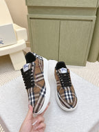 Burberry sneakers held by hand, brown plaid upper with black laces and white sole