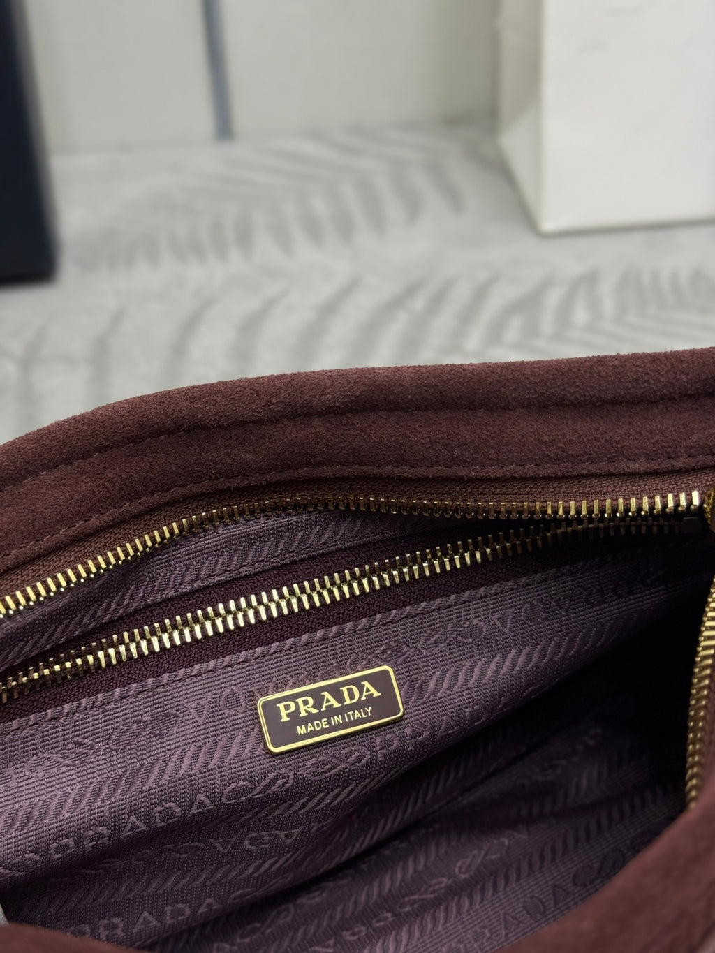 Bag interior with patterned lining, gold zipper, and PRADA logo patch.