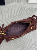 Dark red suede bag open to show interior lining and gold zipper with pull tab.