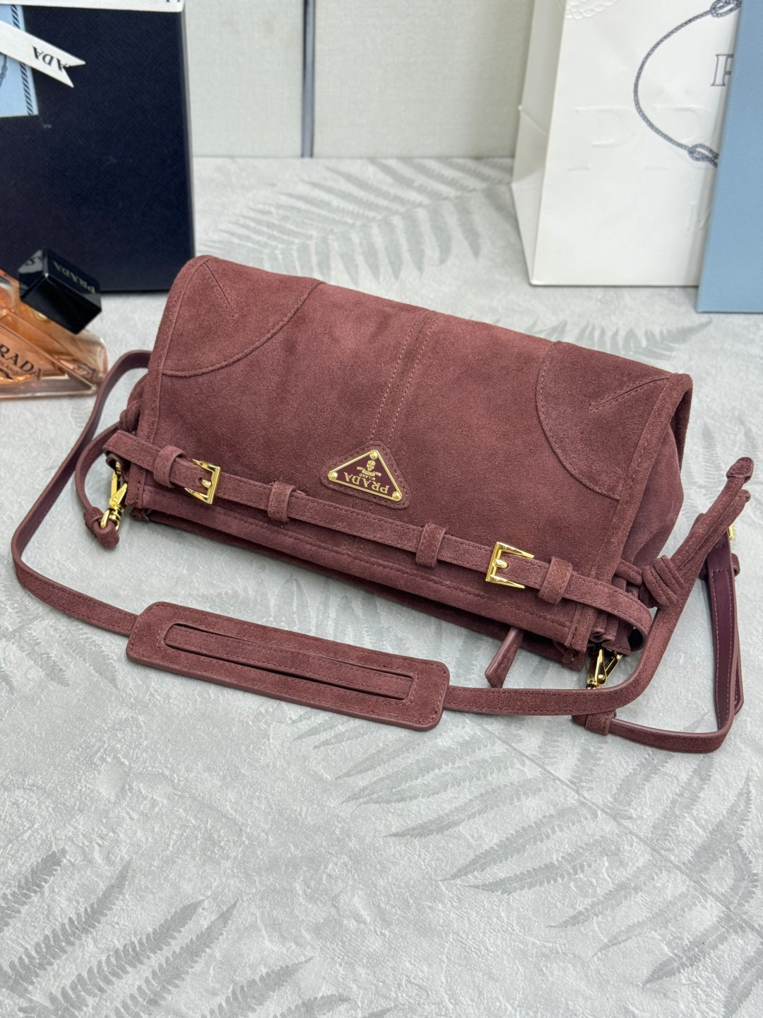 Dark red suede shoulder bag with flap clasp, gold hardware, and attached shoulder strap.