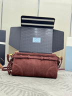 Dark red suede shoulder bag with flap strap and gold hardware, shown front-on.