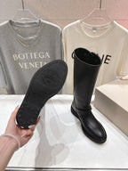 Black boot sole and front view of tall boots, showing embossed tread