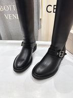 Close-up of two black tall boots with side buckle strap and stacked sole