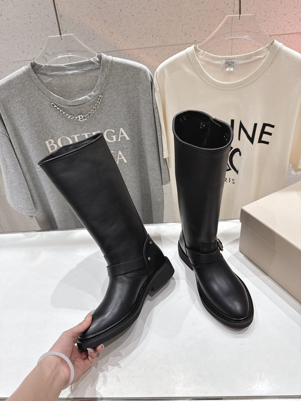 Black tall boots on display with a side buckle strap and thick rubber sole
