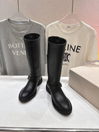 Pair of black tall boots standing side by side, with strap and buckle detail