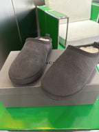 Two dark gray suede slide sandals on display, cream lining visible
