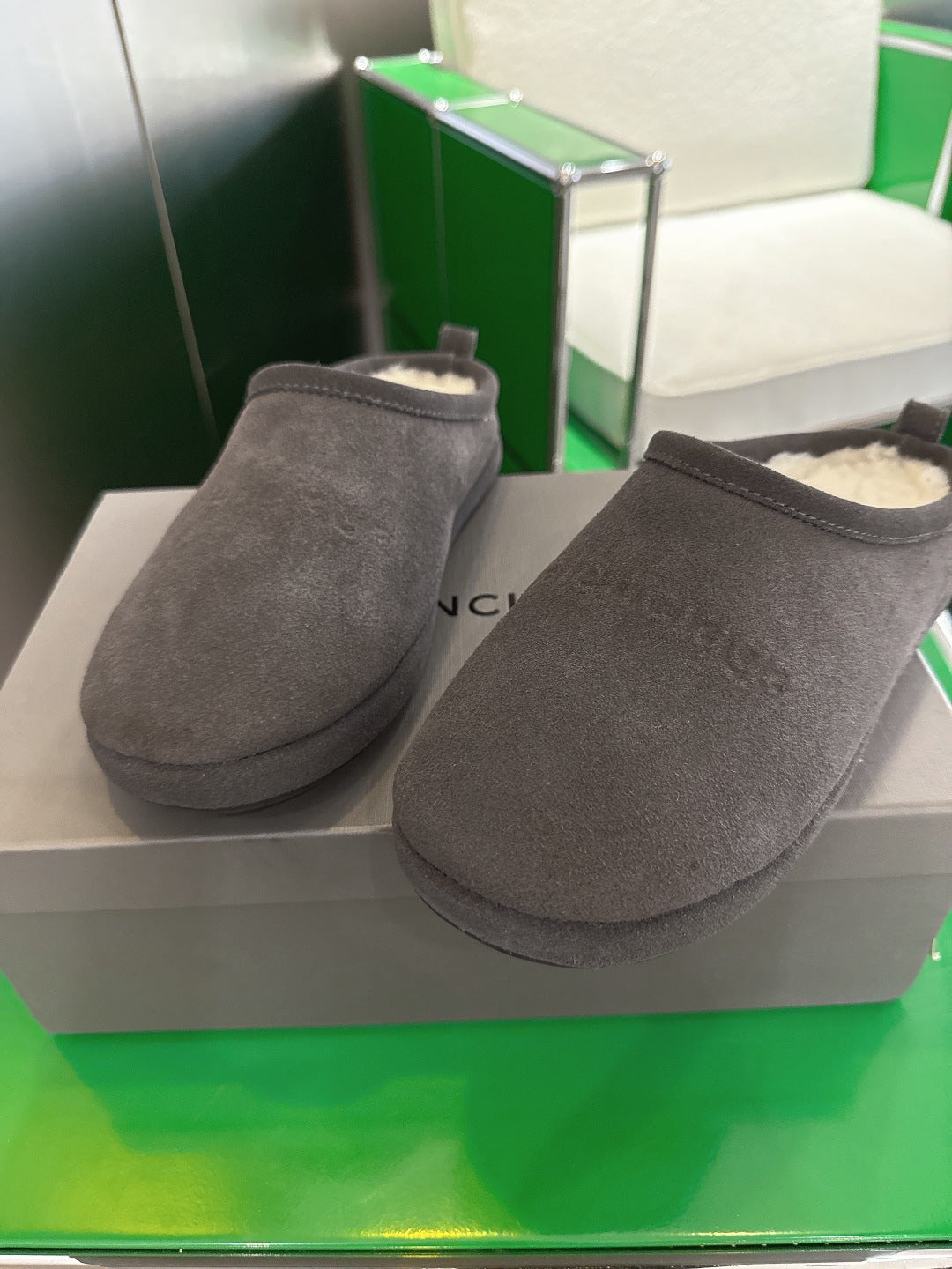 Two dark gray suede slide sandals on display, cream lining visible