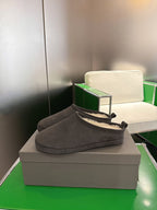 Dark gray suede slide sandal with black tie detail and cream shearling lining