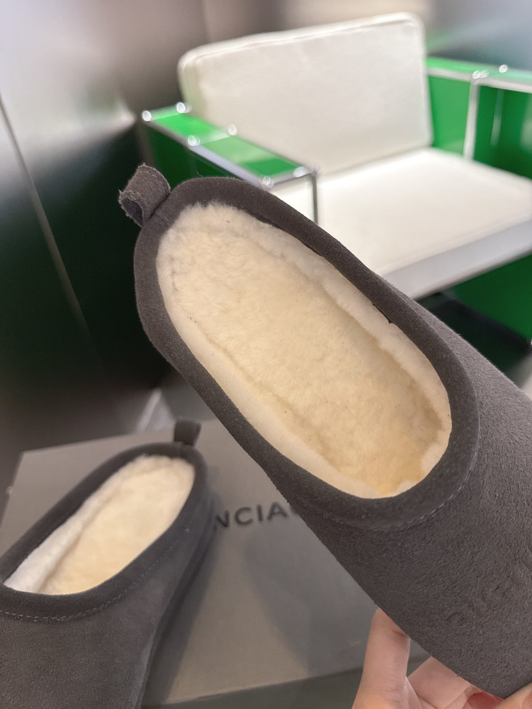Close-up of dark gray suede slide sandals showing cream shearling interior