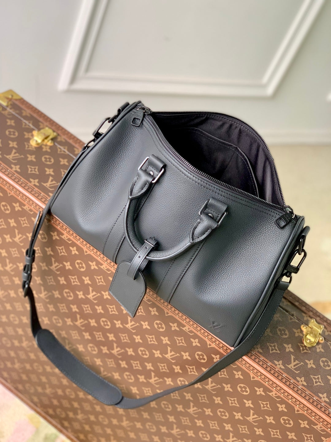 Men's Louis Vuitton duffel bag in dark gray leather with front buckles and shoulder strap.