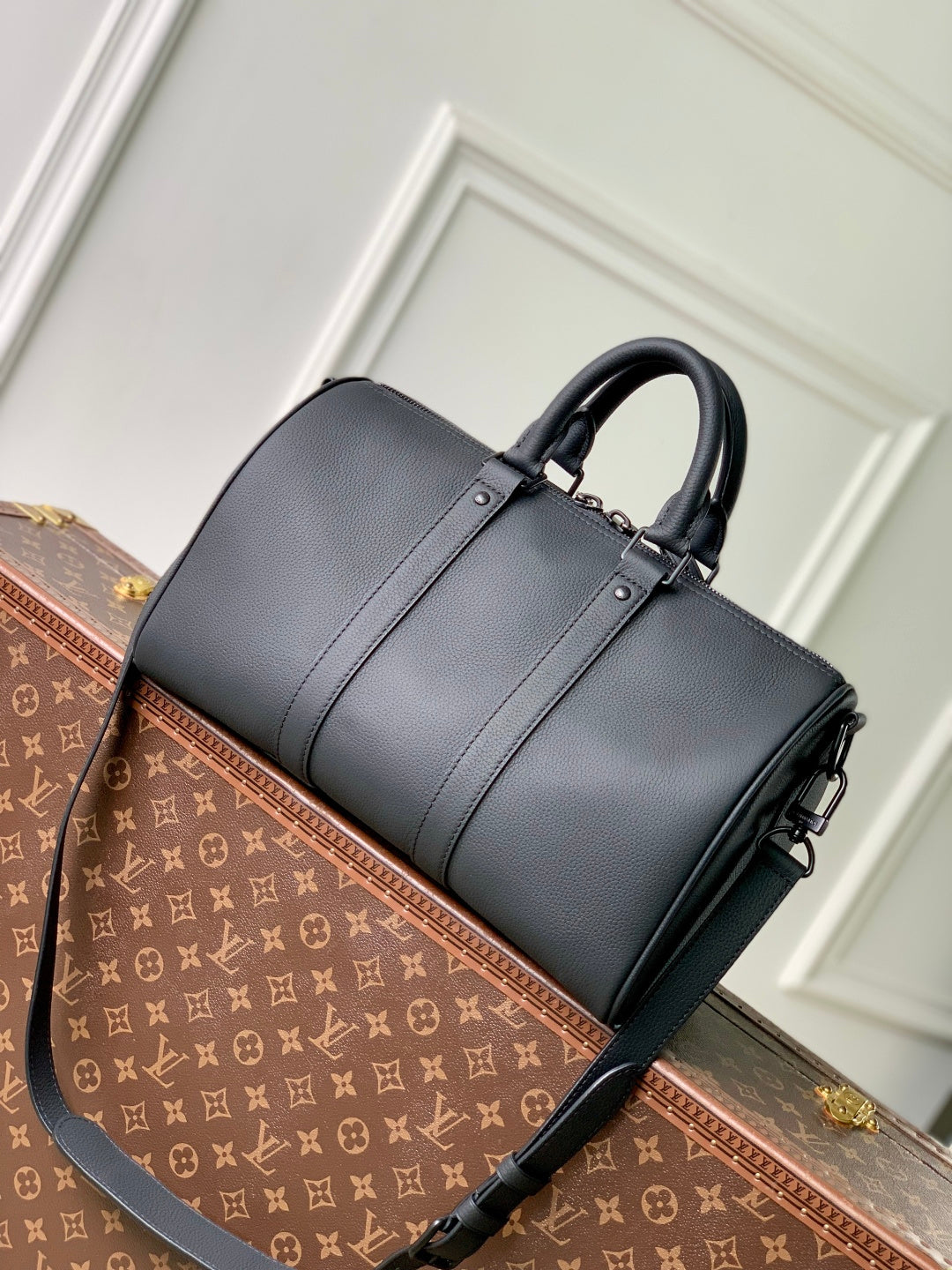 Men's Louis Vuitton duffel bag, dark gray leather with crossbody strap and rounded top.